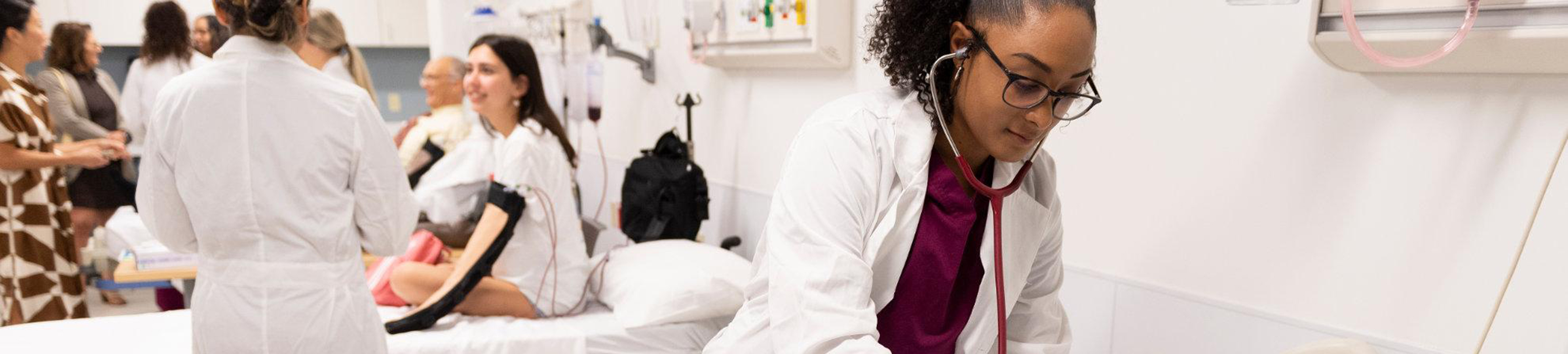 students in white doctor's coats training in hospital lab